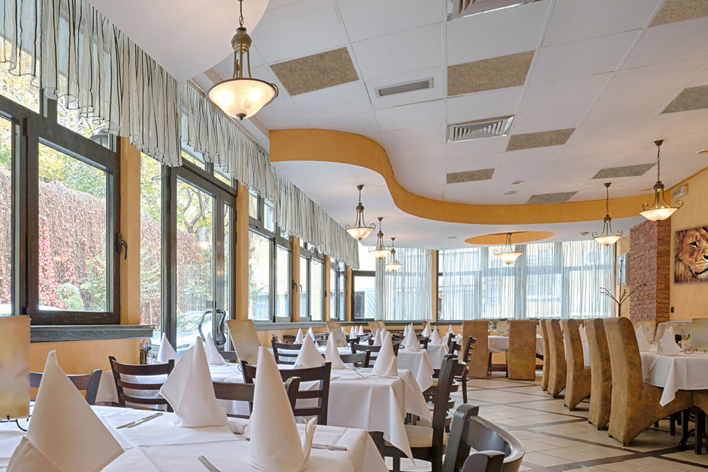 Restaurant with finely laid tables, white and beige acoustic elements are attached to the ceiling Restaurant with finely laid tables, white and beige acoustic elements are attached to the ceiling