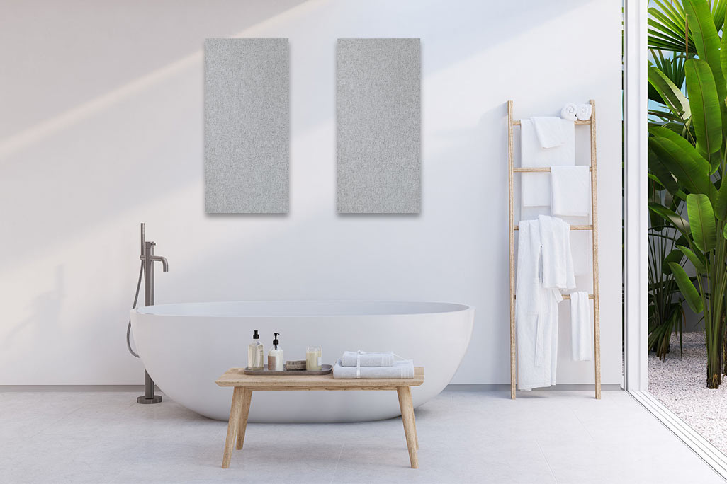 Bright bathroom with a white bathtub and a white wall on which two rectangular acoustic elements in light gray are attached