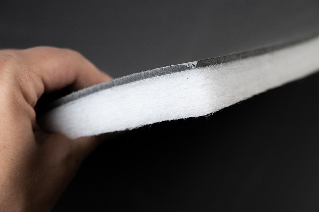 Zwei Schallschutzplatten aus weißem Vlies mit schwarzer Schwerfolie kombiniert wird in der Hand gehalten