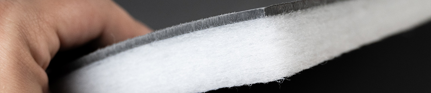 weiße Vliesplatte mit dicker Schwerfolie wird von einer Hand hochgehalten