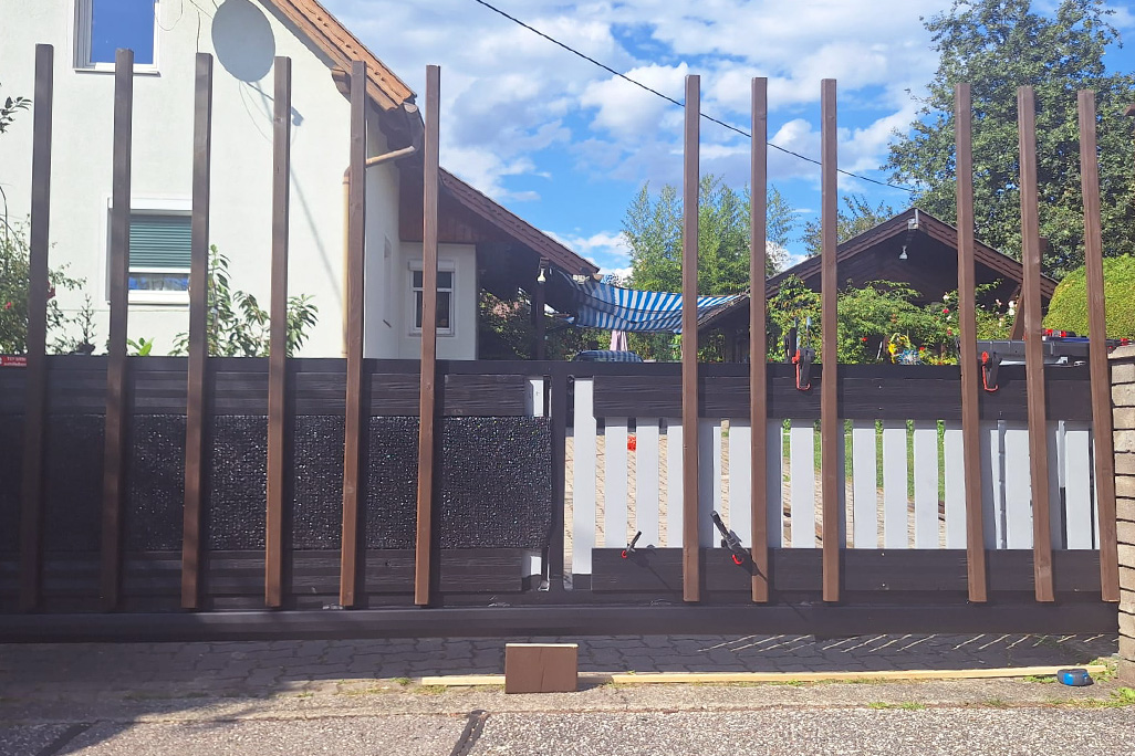 Zufahrtstor mit Schallschutzplatten hinter Holzleisten