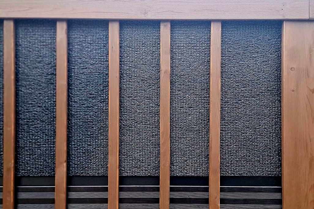 Zufahrtstor mit Schallschutzplatten hinter Holzleisten