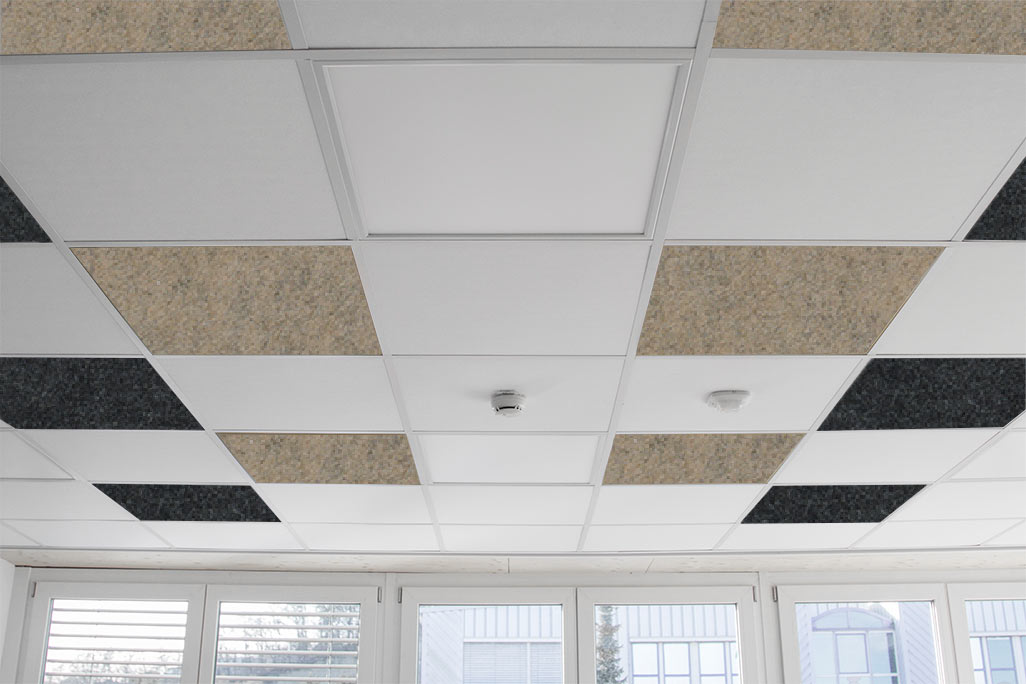 Grid ceiling in an office with square, colored inlaid acoustic elements in white, beige and anthracite.