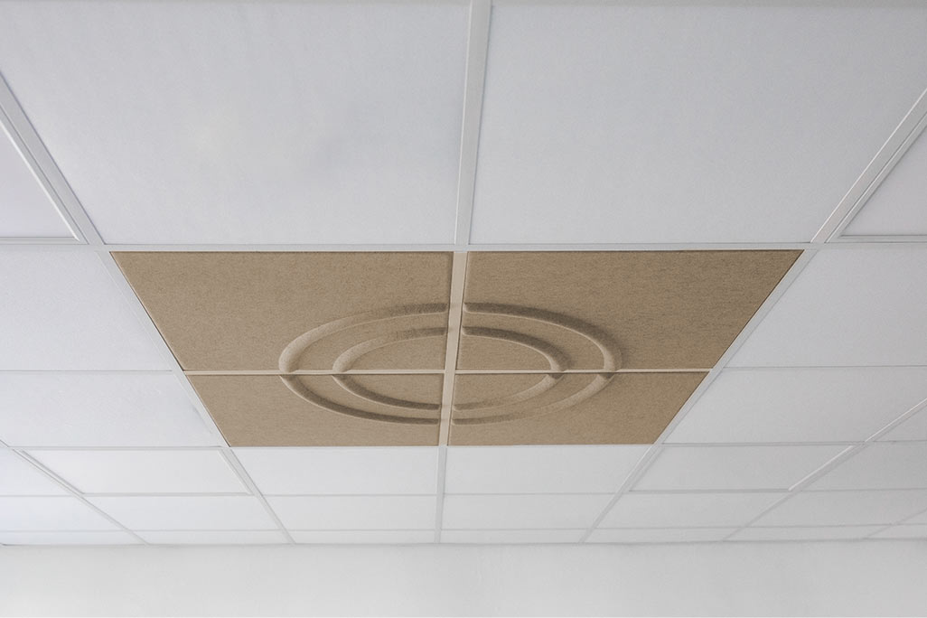Section of a standard grid ceiling with inlaid soni COMFORT SD acoustic absorbers in white and soni COLOR Design in beige.