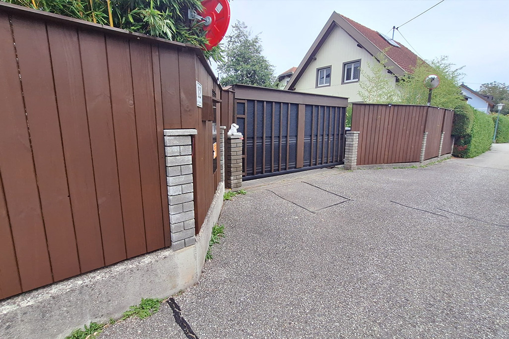 Zufahrtstor mit Schallschutzplatten hinter Holzleisten